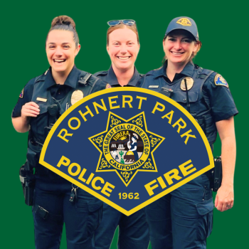 Three women in police uniforms standing in front of a green background with the department logo