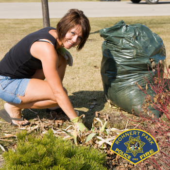 Women clearing dry leaves from yard with full garbage bag and rake
